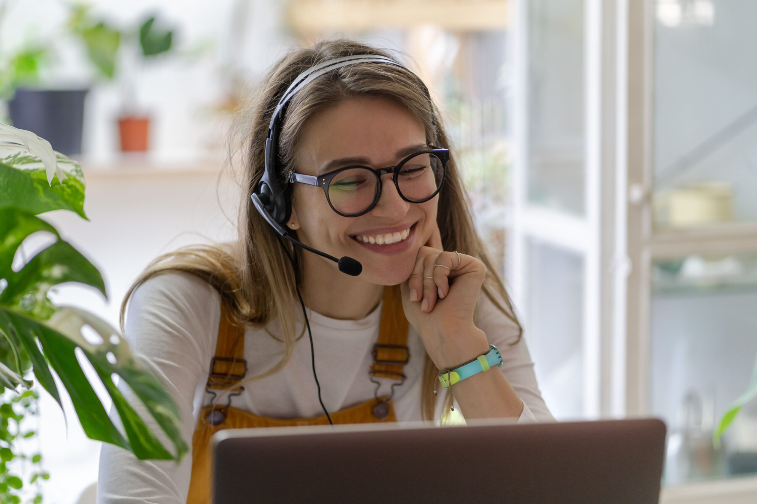 Smiling woman with headset working at laptop – confident in pursuing unconventional side gigs like OnlyFans job application or remote work